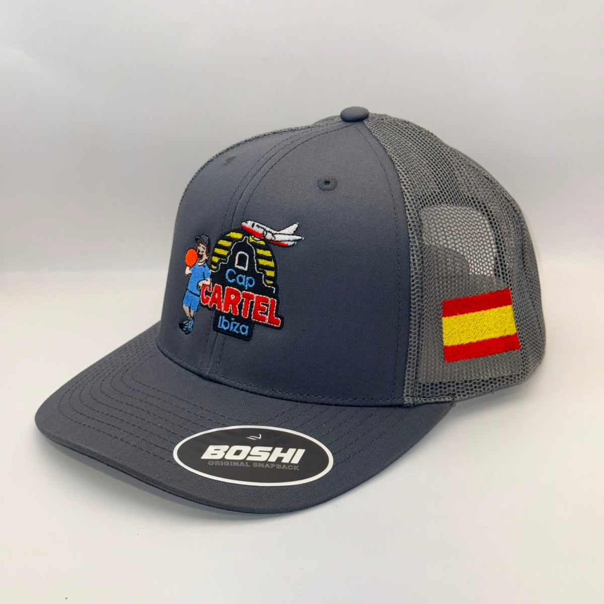 A dark gray mesh-back trucker hat with a curved brim, featuring a colorful 'Copa Cartel' graphic on the front, a Spanish flag patch on the side, and a white oval 'BOSHI' logo sticker on the brim.